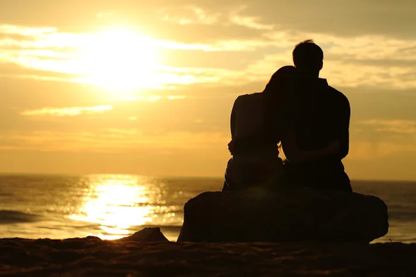 Coppia silhouette guardando il tramonto sulla spiaggia — Foto Stock