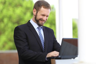 Bir dizüstü bilgisayar açık tarama Internet çalışma mutlu iş adamı