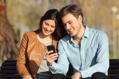 Bir bankta oturan bir akıllı telefon izlerken Çift
