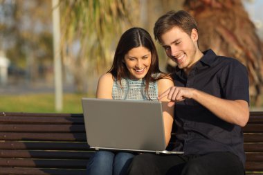 Bir bankta oturan bir laptop medya izlerken Çift