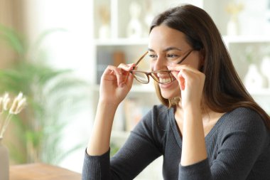 Mutlu kadın gözlük takıyor ve evin içinde gülümsüyor.