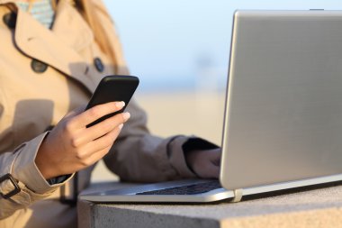 Kendini bir dizüstü bilgisayar ve telefon ile çalışan kadın istihdam