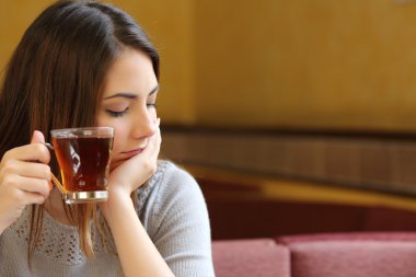 Genç kadın bir fincan çay tutan bir kahve dükkanında rahat