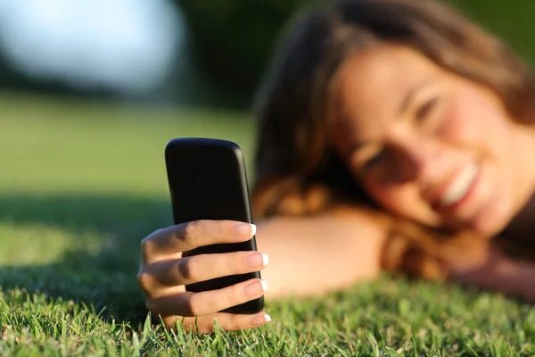 Zblízka šťastné teen holka ruky pomocí chytrý telefon na trávě — Stock fotografie