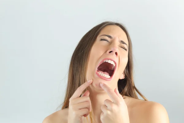 Girl crying while pressing a pimple on her chin — Stock Photo, Image