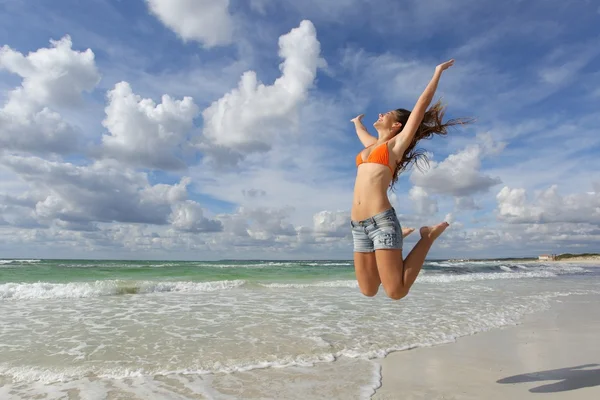 Happy girl jumping on the beach on holidays — Stock Photo, Image