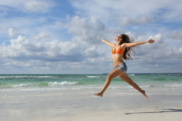 Glückliche Frau, die im Urlaub am Strand springt — Stockfoto