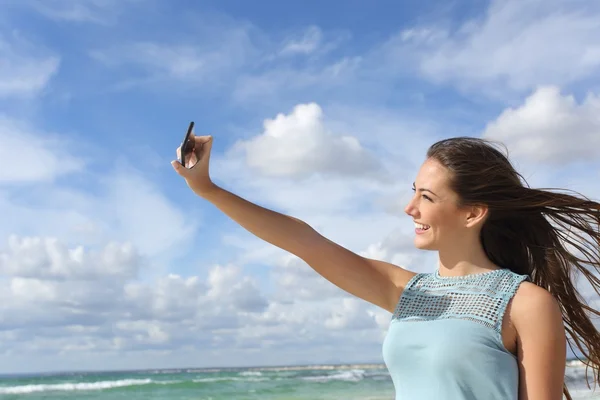 Mädchen fotografiert ein Selfie mit dem Smartphone am Strand — Stockfoto