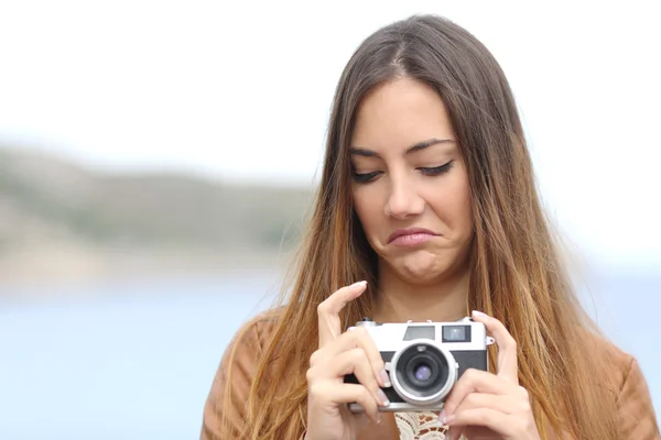 Mulher perturbada olhando sua antiga câmera de fotos slr — Fotografia de Stock