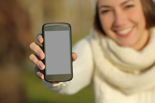 Mujer mostrando una pantalla de teléfono inteligente en invierno al aire libre —  Fotos de Stock