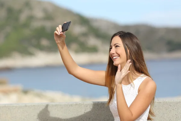 Saludo de la mujer mientras fotografía una selfie con un smartphone — Foto de Stock