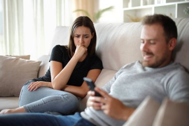 Üzgün kadın ve partneri onu görmezden geliyor ya da evdeki bir kanepede oturuyor.