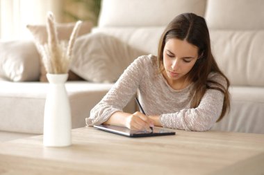 Evdeki kahve masasında dijital tablette ciddi bir kadın el yazısı.