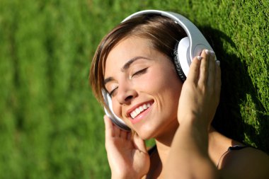 Mutlu kız bir parkta kulaklık ile müzik dinlemek
