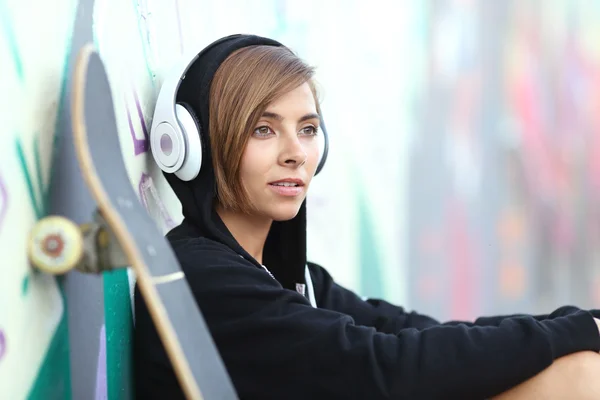 Jovem skatista ouvindo a música com fones de ouvido — Fotografia de Stock