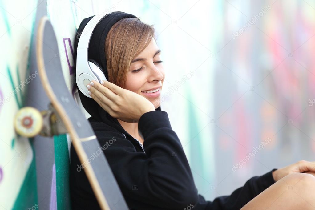 Skater teen girl listening to the music with headphones