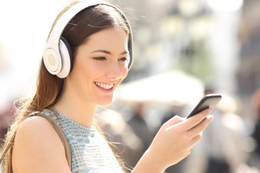 Kadın sokakta bir akıllı telefon üzerinden müzik dinleme