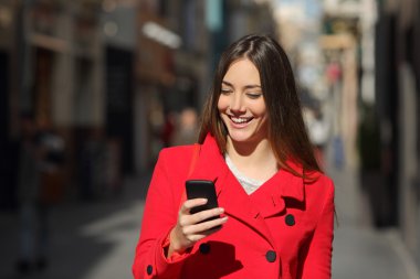 Caddede yürüyüş sırasında bir akıllı telefon kullanan kadın