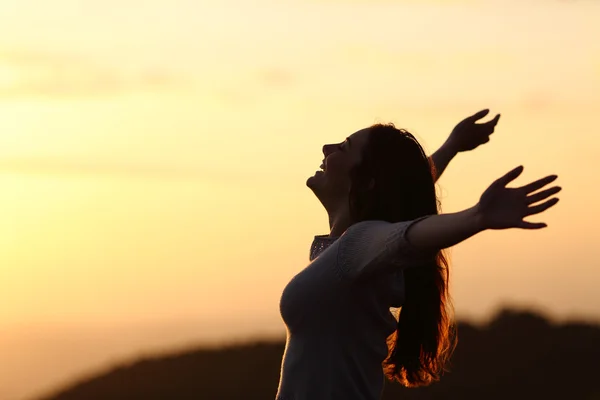 Back light of a woman breathing raising arms — Stock Photo, Image