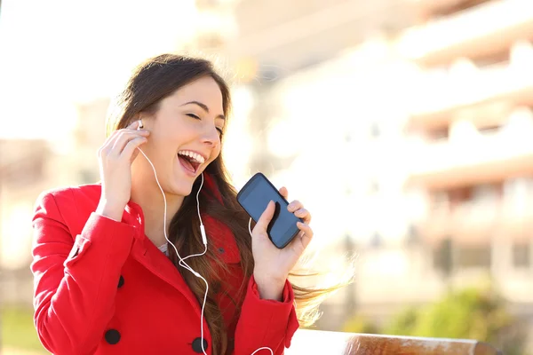 Menina engraçado ouvir a música com fones de ouvido de um telefone — Fotografia de Stock