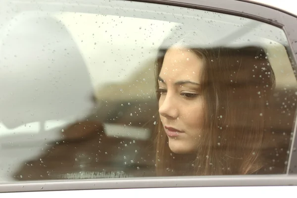 Mulher triste olhando através de uma janela de carro — Fotografia de Stock