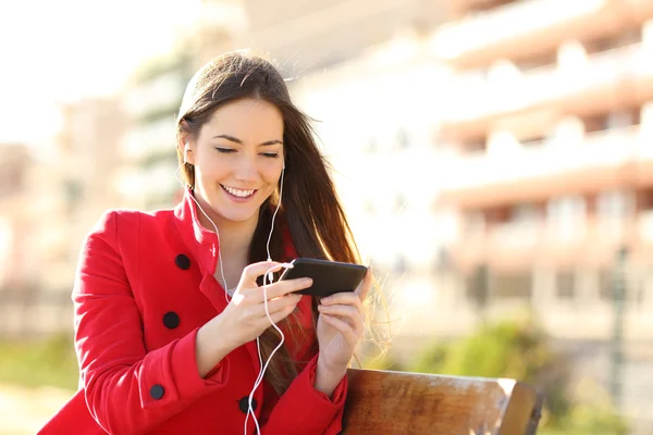 Donna che guarda video in uno smartphone con gli auricolari — Foto Stock