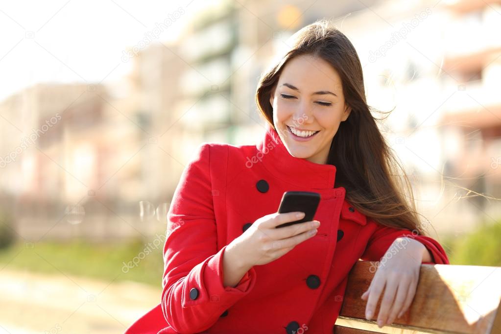 Girl texting on the smart phone sitting in a park