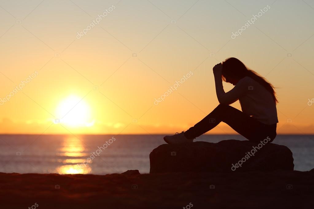 Silhueta de mulher triste preocupado ao pôr do sol