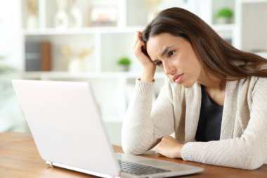 Kafası karışık ve endişeli bir kadın evde dizüstü bilgisayar içeriğini kontrol ediyor