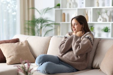 Kışın süveteri kapan, evdeki kanepede oturarak ısınan tatmin olmuş bir kadın. 