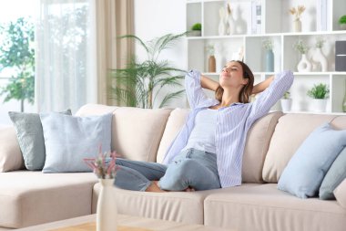 Mavili kadın evdeki kanepede dinleniyor.