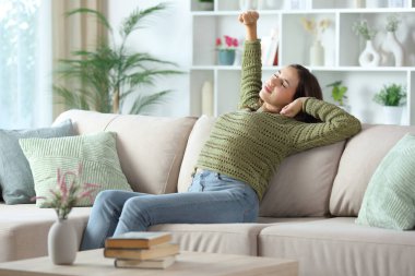 Yeşilli kadın şekerleme yaptıktan sonra evdeki kanepede oturuyor.