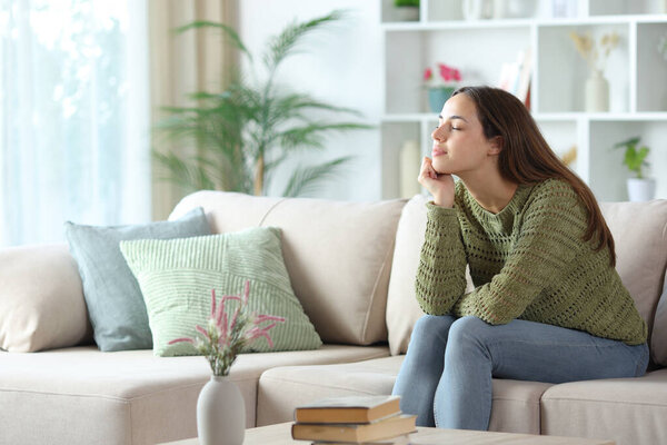 Relaxed woman in green resting on a couch at home