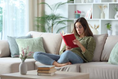 Yeşilli, kafası karışmış bir kadın. Evdeki kanepede oturmuş kitap okuyor.