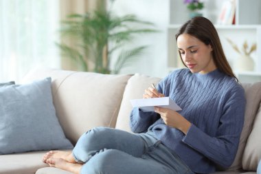 Evdeki kanepede oturan mavi elbiseli kadın.