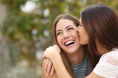 Two funny women friends laughing and kissing clipart