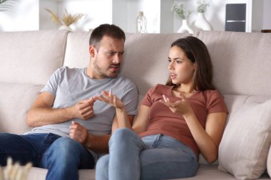 Çift konuşuyor ve evdeki kanepede oturuyor.