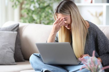 Evdeki koltukta oturup medya içeriğini seyreden mutlu bir kadın.