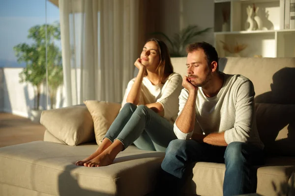 Evdeki kanepede gözleri kapalı oturan bir çift.