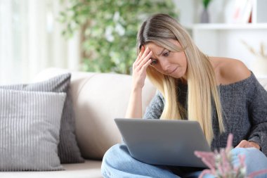 Hatadan sonra şikayet eden bir kadın evdeki kanepede oturup dizüstü bilgisayarını kontrol ediyor.