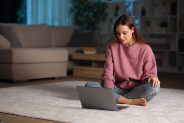 Gecenin bir yarısı dizüstü bilgisayar kullanan bir kadın.