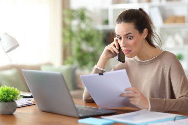 Evdeki kağıt bilgileri hakkında telefonda konuşan kafası karışık bir serbest meslek.