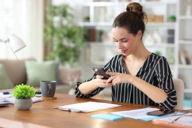 Ücretsiz çalışan kağıt sözleşmesinin fotoğrafını çekmek için evde telefon kullanıyor.