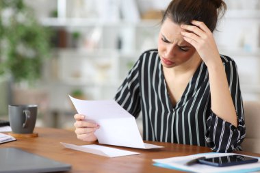 Evde çalışırken kötü haberler okuyan serbest çalışan endişeli bir işçi.