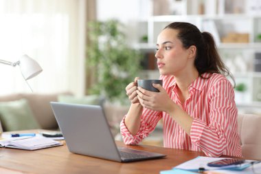 Dikkati dağılmış serbest çalışan, kafasını çevirmiş, kahve molası veriyor, evde çalışıyor.