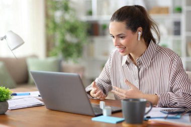 Ev içinde çalışan kulaklıklar ve dizüstü bilgisayarla video araması yapan mutlu bir televizyon çalışanı.