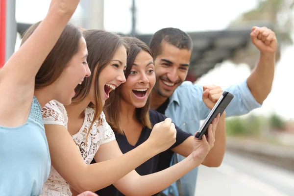 Cuatro amigos eufóricos viendo una tableta — Foto de Stock