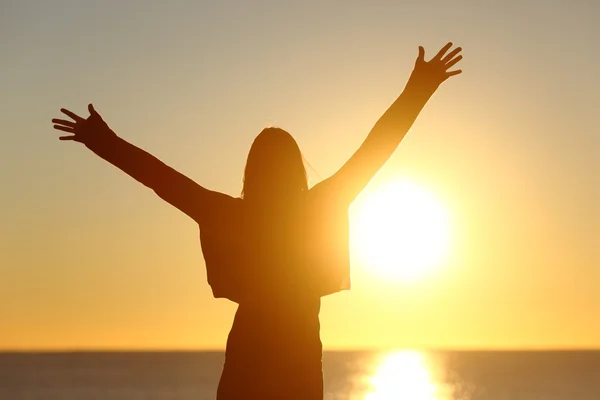 Femme libre levant les bras regardant le soleil au lever du soleil — Photo