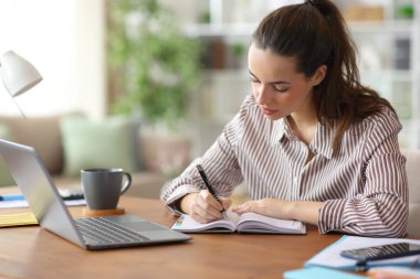 Evde çalışan ciddi girişimci kağıt gündemine notlar yazıyor.