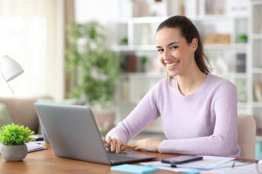 Evde kameraya bakan bir dizüstü bilgisayarla çalışmaktan mutlu.